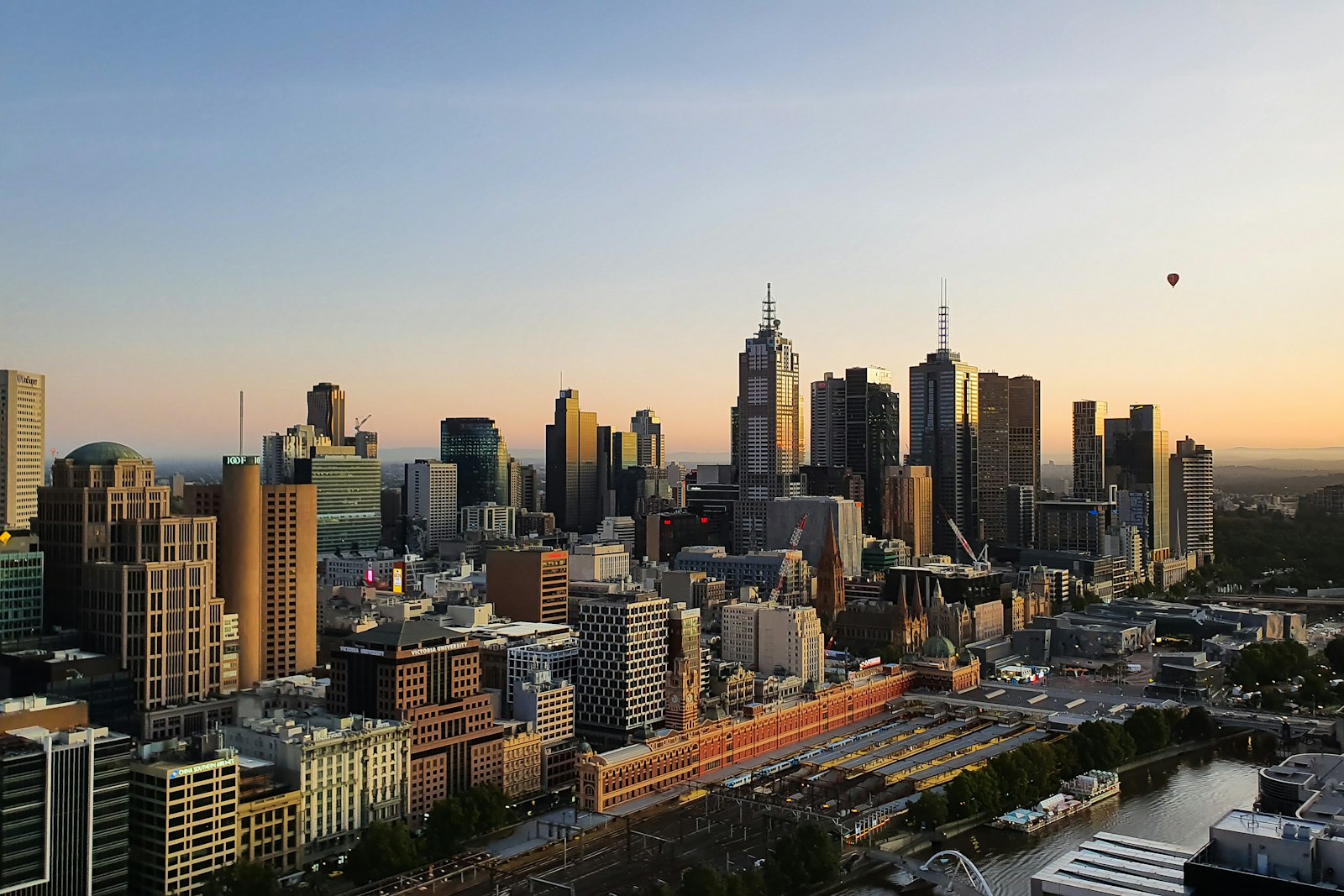Melbourne city skyline at sunrise with hot air balloons overhead